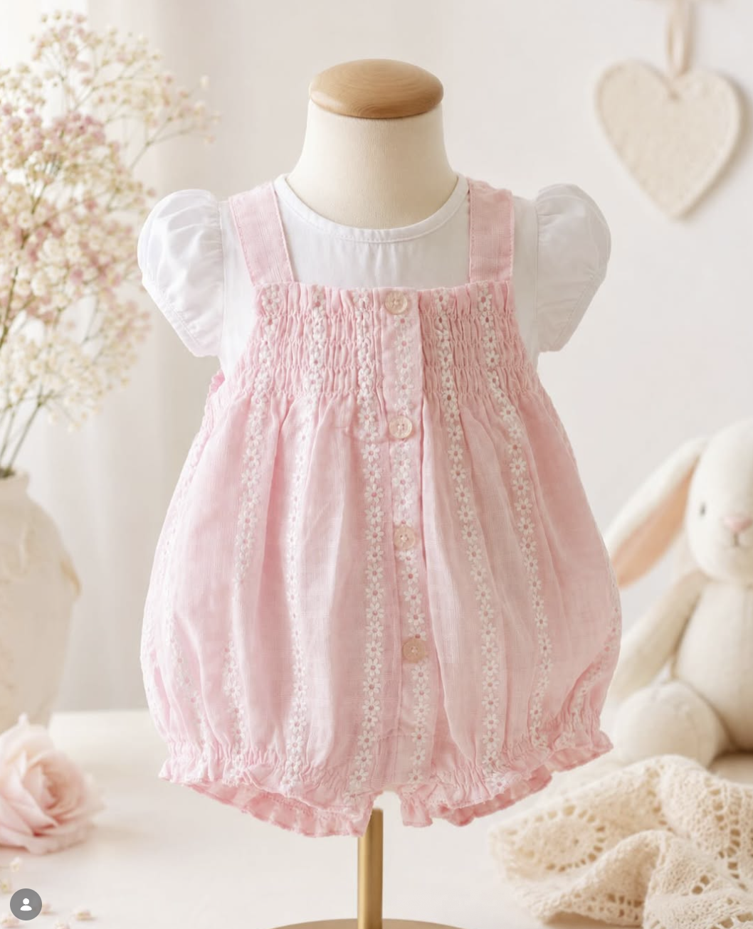 Pink smocked romper for girls on mannequin.
